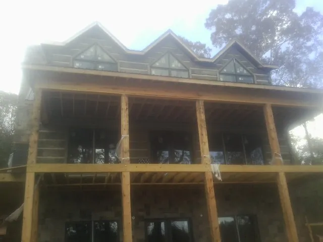 Dormers and porch framing on a large log home under construction — Roof Coating work by our crew in Mooseheart