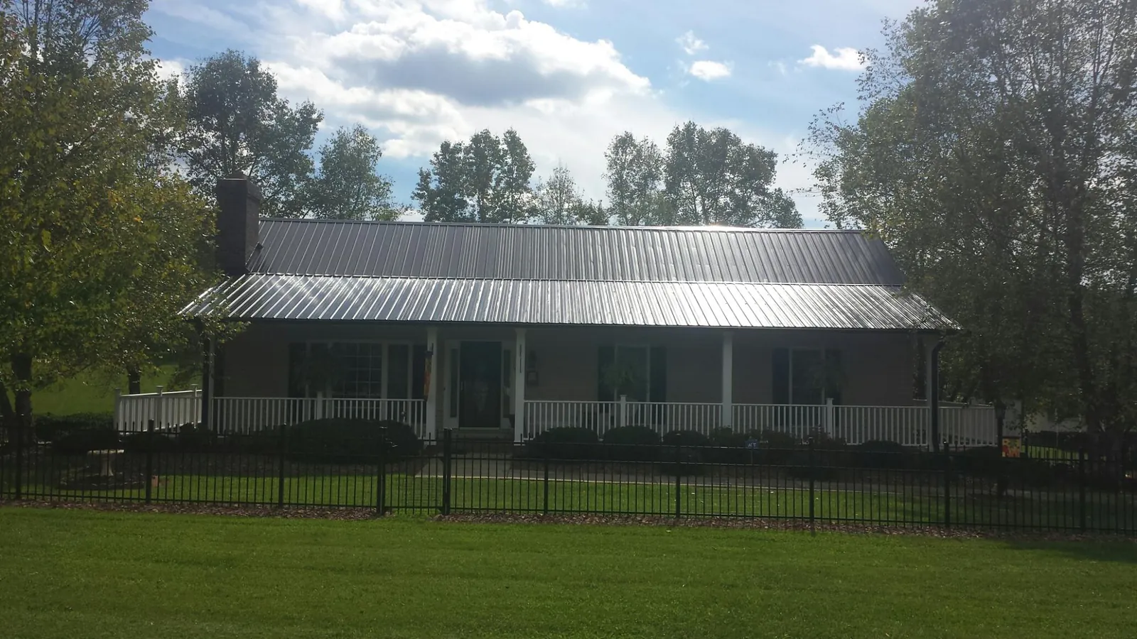 Gray metal roof on a brick ranch with a full width front porch in Mooseheart