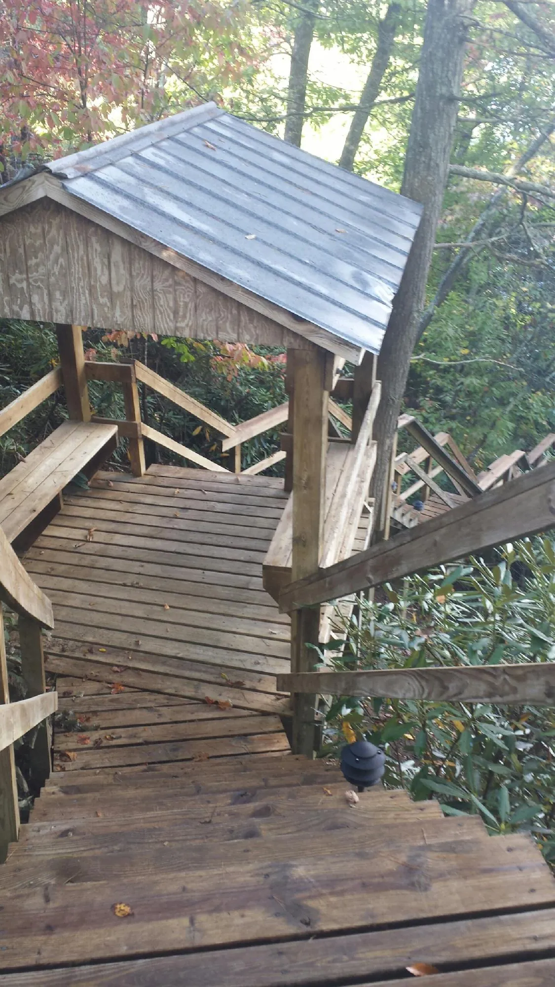 Metal roofed shelter over wooden steps on a wooded walkway — Skylight Repair & Installation work by our crew in Mooseheart