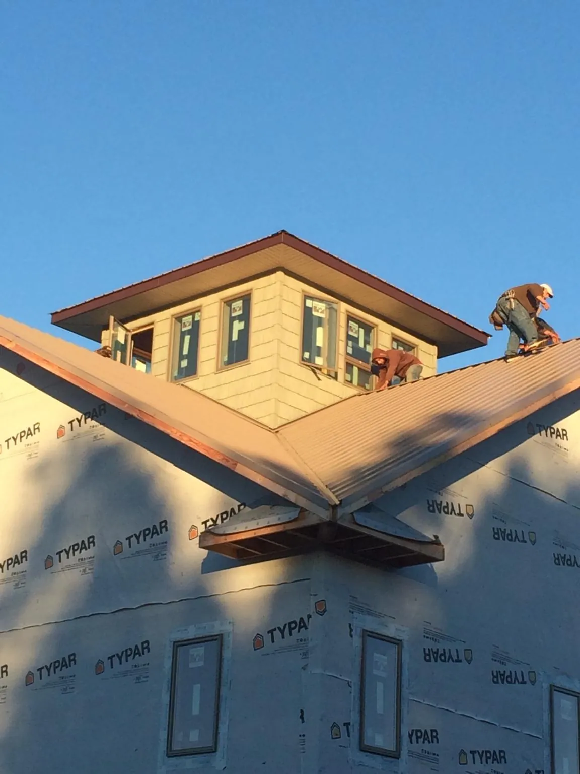 Roofers working around a rooftop cupola on a new metal roof at sunset — Roof Waterproofing in Mooseheart by Roofing Brothers